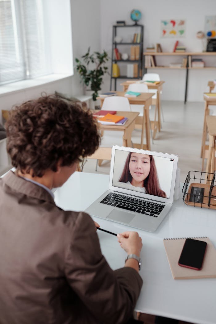 A student in a classroom takes an online lesson via a video call, illustrating modern education technology.